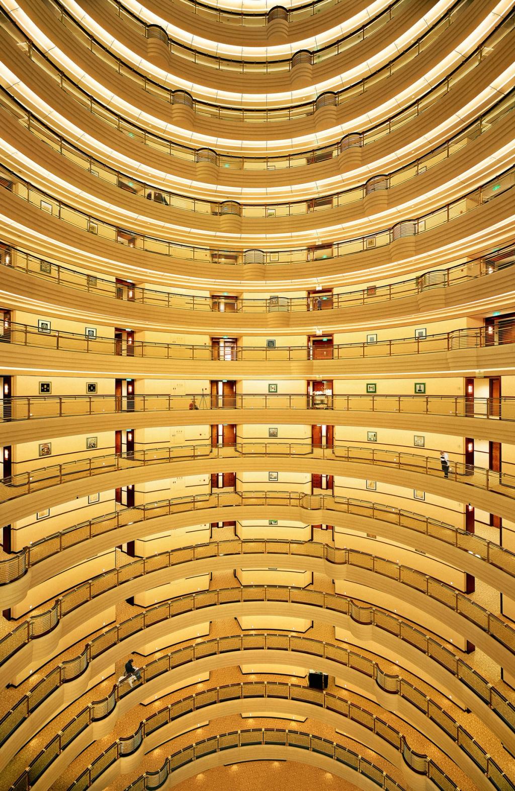 The interior atrium of a high-rise hotel: concentric tiers of balconies receding upward
