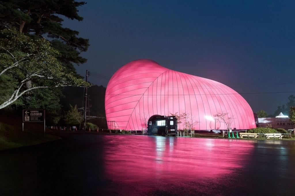 The Ark Nova inflatable concert hall at night, its pink pneumatic shell lit from within