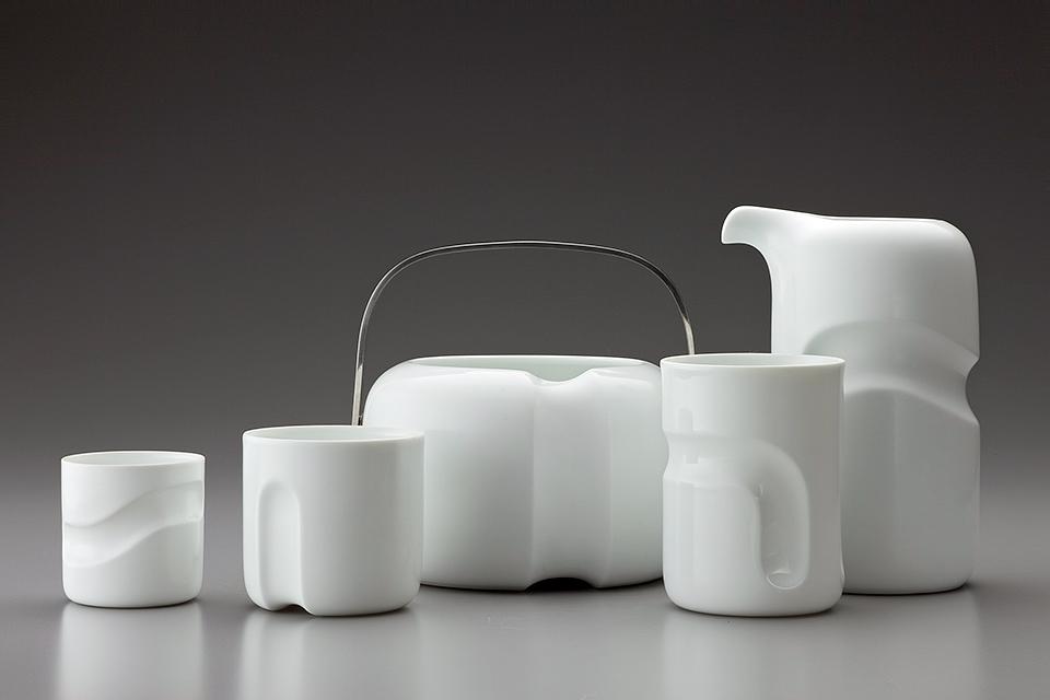 White porcelain tea set with a wavy relief and a metal handle