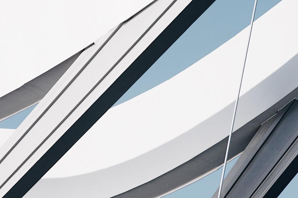 The white curved arches of the Infinity Bridge in close-up against a bright sky
