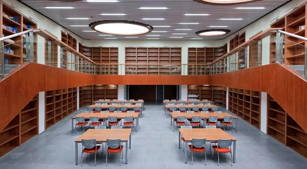 The double-height reading room of Liyuan School's library, with built-in wooden shelving and desks