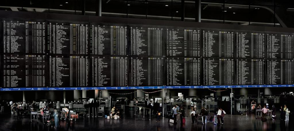 A vast departures board in an airport terminal, with check-in desks and passengers beneath it