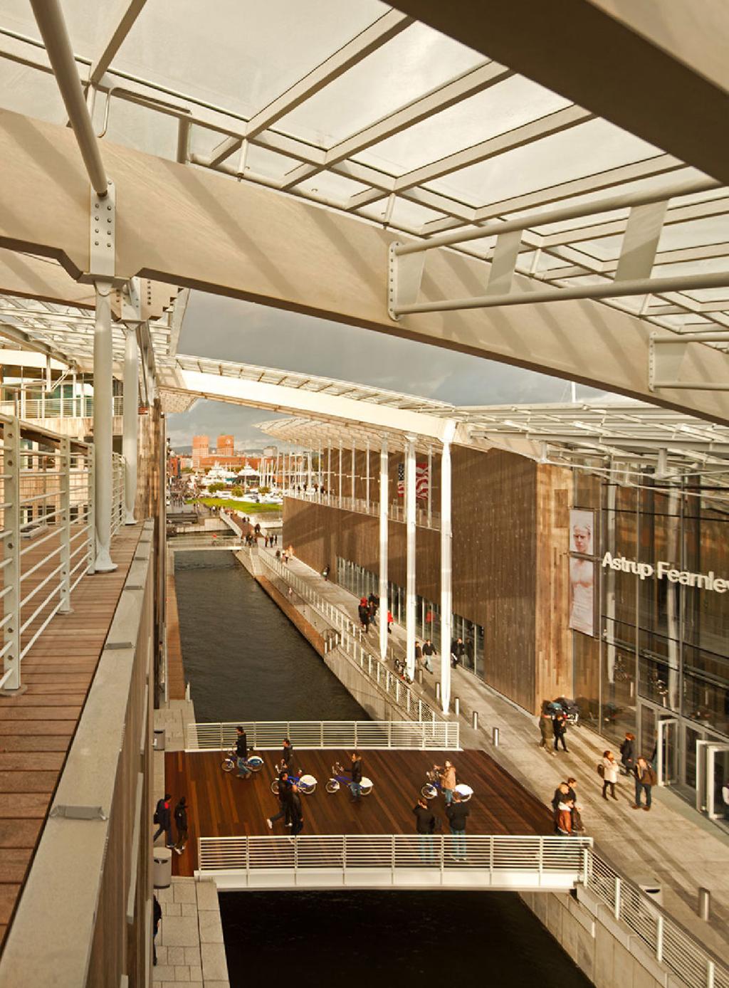 The Astrup Fearnley Museum with the canal and wooden waterfront promenade, Oslo City Hall visible in the distance
