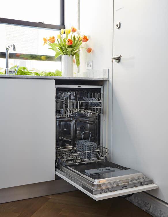 Встроенная узкая посудомоечная машина SMEG с открытой дверцей под кухонной столешницей