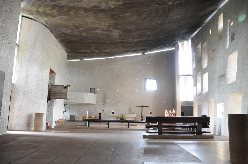 Interior of the Chapel of Ronchamp, with a curved ceiling and light-filled apertures in the wall