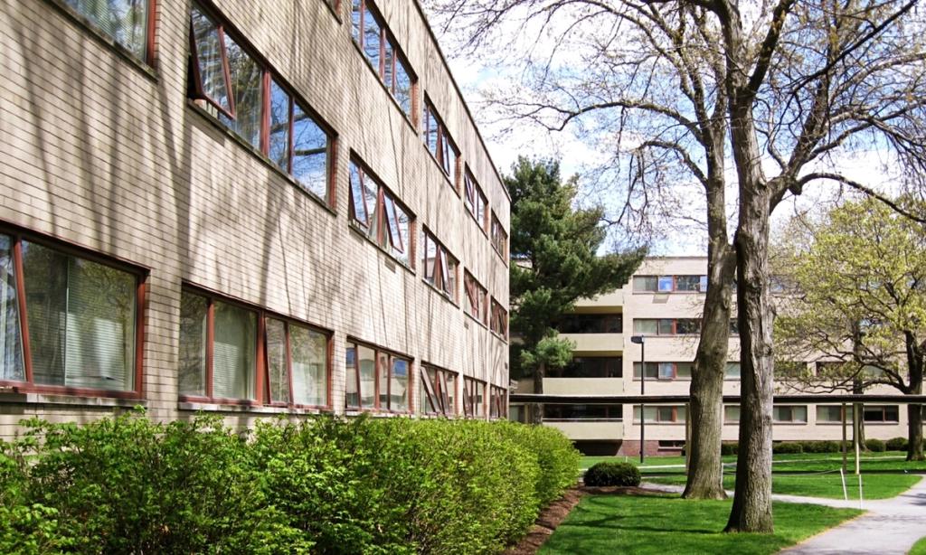 The brick dormitory buildings of the Harvard Graduate Center with ribbon windows set among greenery