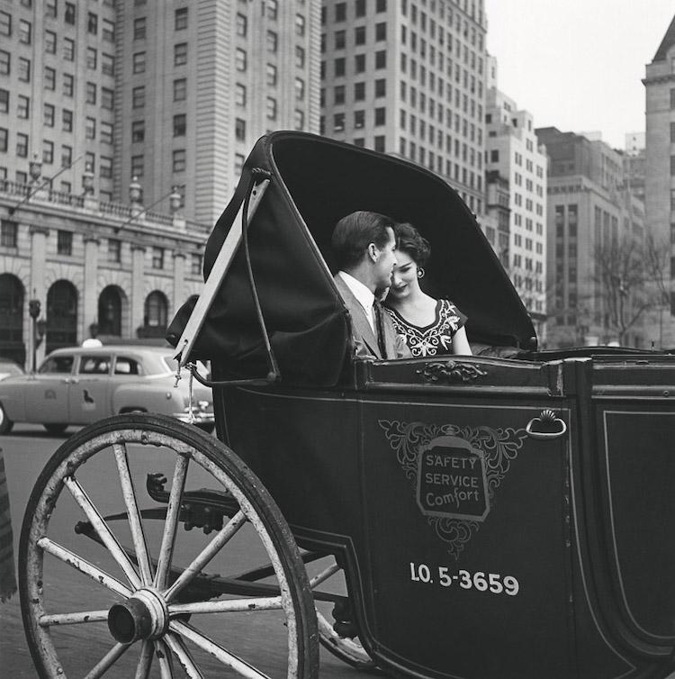 Black-and-white photograph: a couple in a horse-drawn carriage against a backdrop of tower blocks, with the words Safety Service Comfort