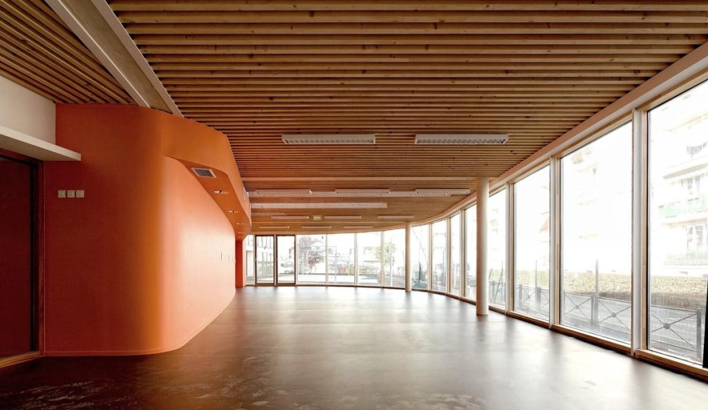 The bright hall of Ecole Jean-Moulin school with an orange wall, wooden ceiling and panoramic glazing