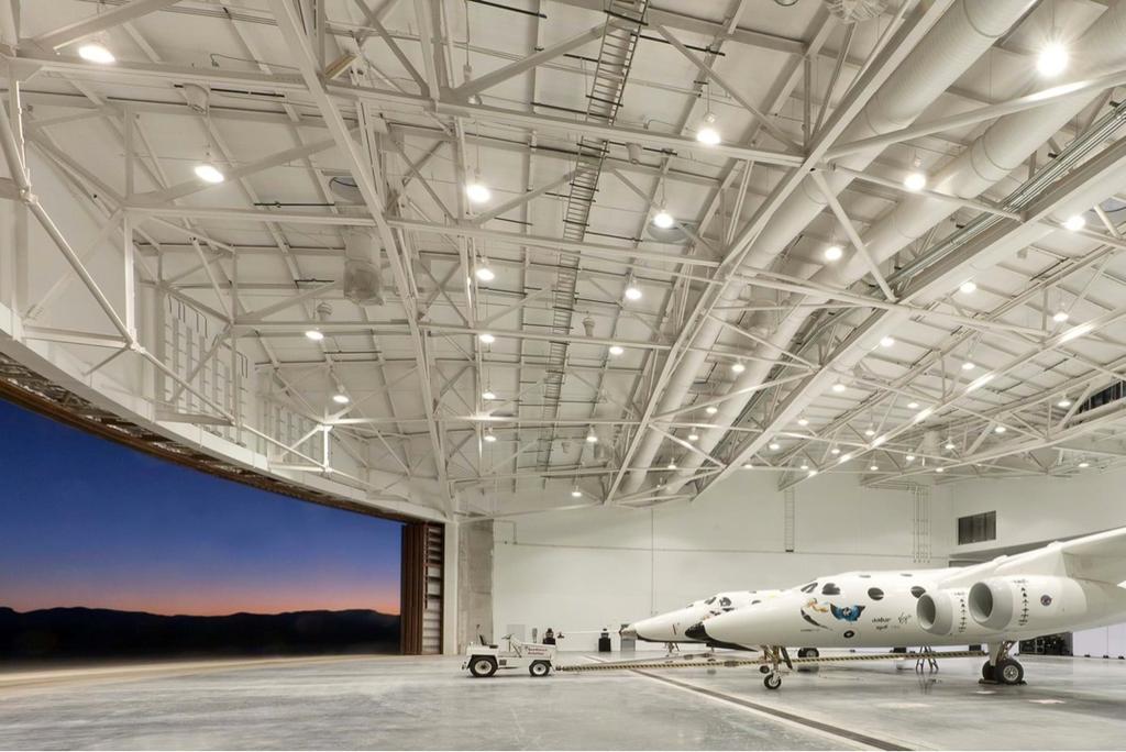 SpaceShipTwo in the bright hangar of Spaceport America with a view of the sunset