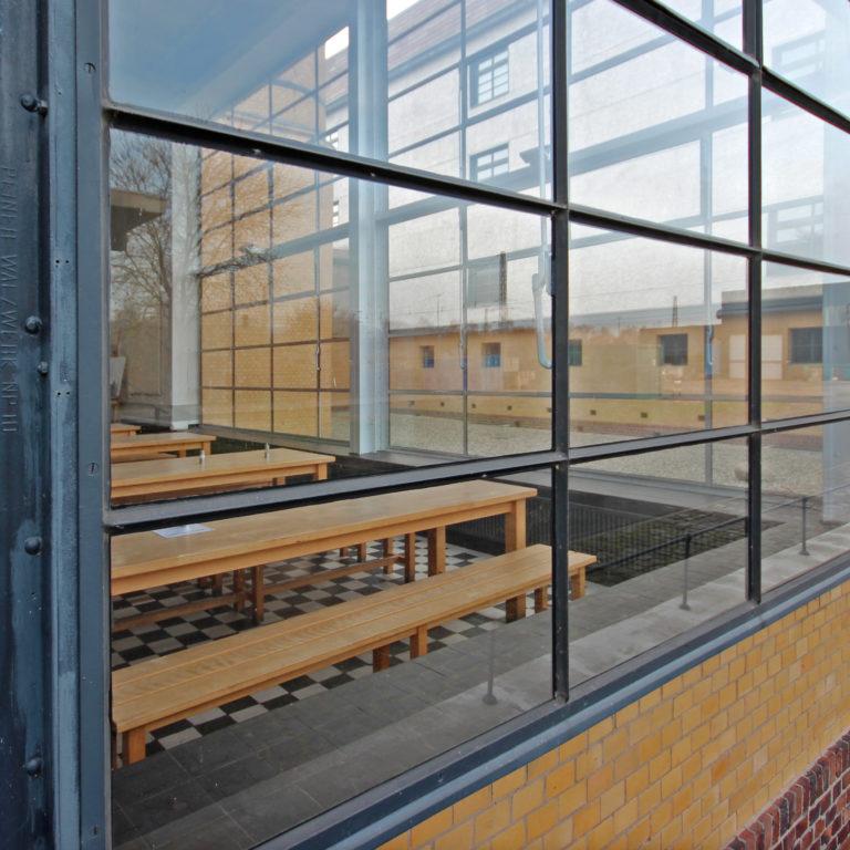 Interior of the Fagus Factory: wooden tables and benches behind a continuous glass facade