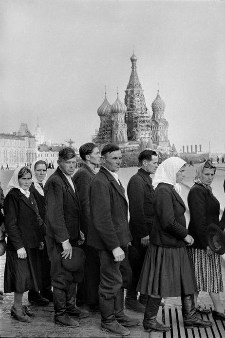 A queue of workers in headscarves and jackets on Red Square, with St Basil's Cathedral in the background