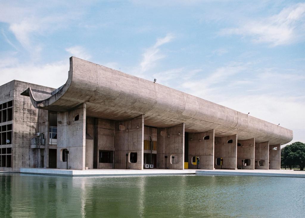 The Palace of Assembly in Chandigarh, with a curved concrete canopy over the portico reflected in a pool of water