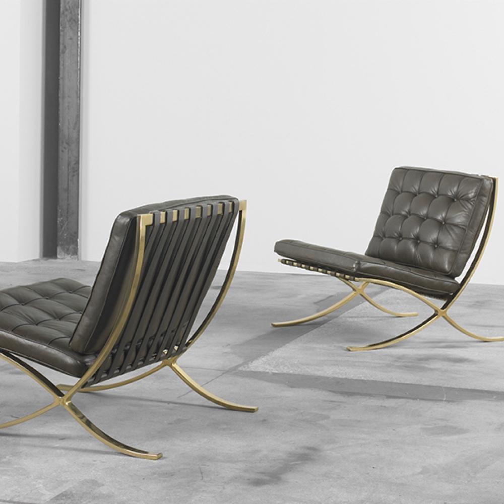 A pair of Barcelona Chairs with dark quilted leather and brass cross-leg bases