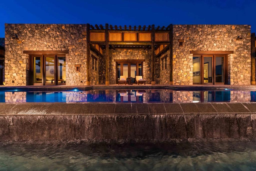 The stone villa at Alila Jabal Akhdar, with its pool glowing in the blue dusk