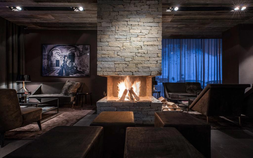 The Hotel Zhero lounge with a burning stone fireplace and dark upholstered furniture