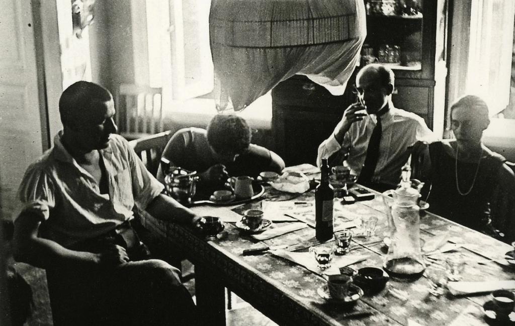 At the table in the Gendrikov Lane apartment. On the right: editor and literary critic Osip Beskin ("little Beskin," in Viktor Shklovsky's phrase) and Lilya Brik. On the left: Mayakovsky. At the head of the table: the artist Varvara Stepanova. Photograph by Alexander Rodchenko. June 1926