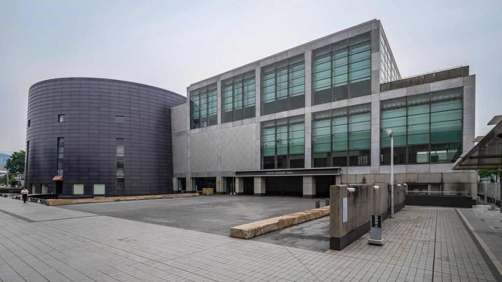 The stone facade of the Kyoto Concert Hall with an adjoining dark cylindrical volume