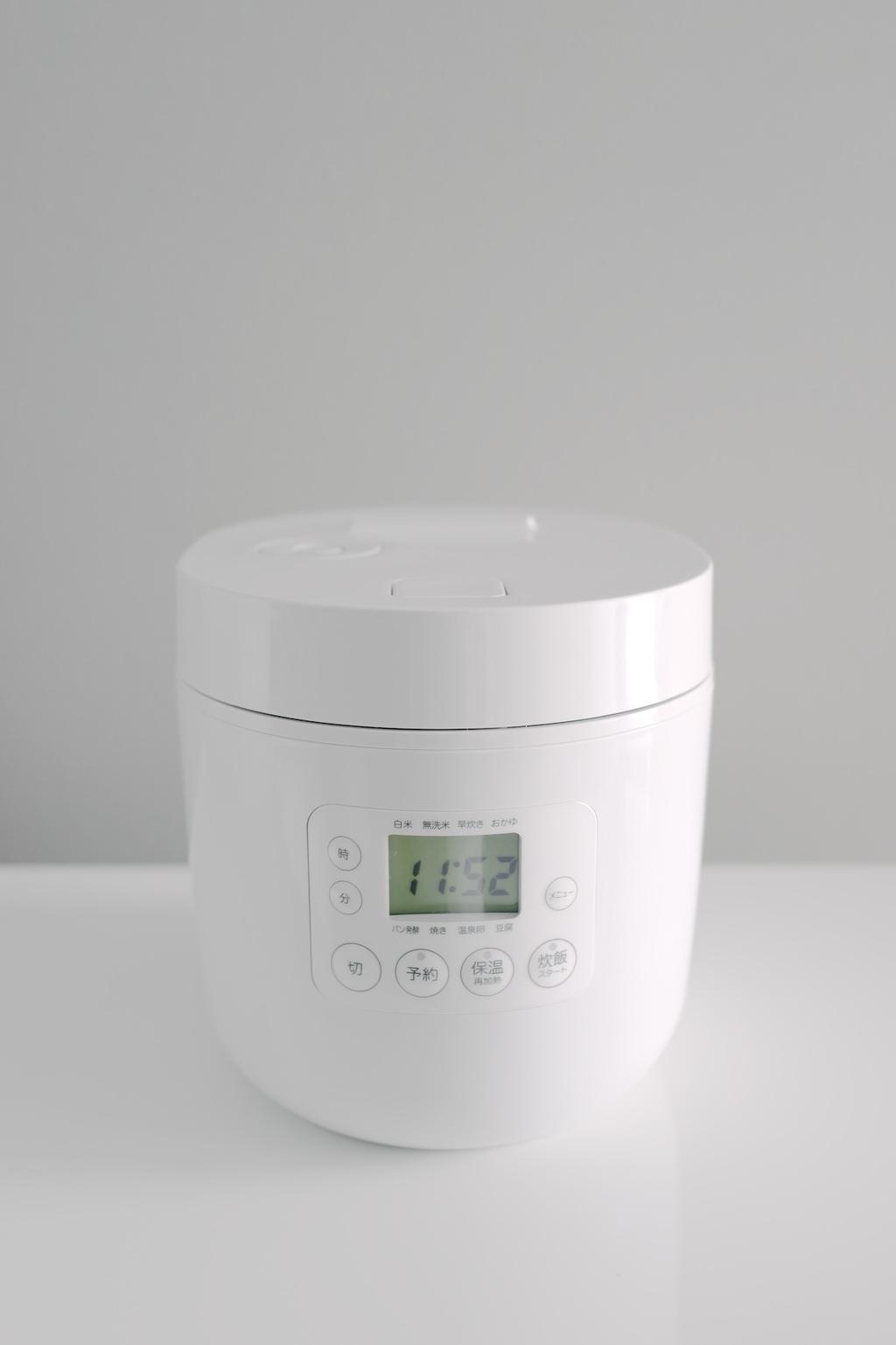 A white rice cooker with a digital display and Japanese text on the control panel