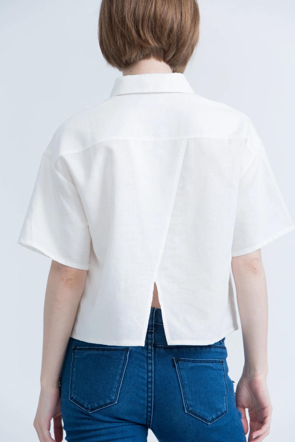 A girl seen from behind in a white cropped Kestan shirt with a slit and blue jeans