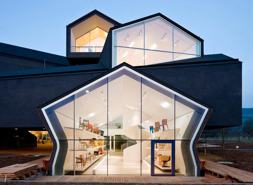 Подсвеченные изнутри стеклянные торцы домиков VitraHaus в синих сумерках