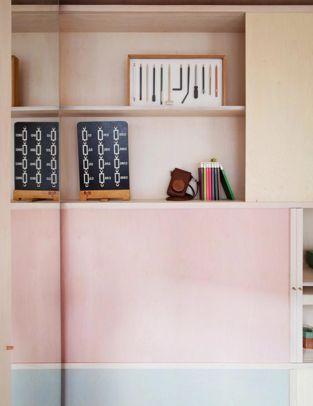 Фанерные полки с книгами, карандашами в рамке, винтажным фотоаппаратом и розово-голубыми панелями