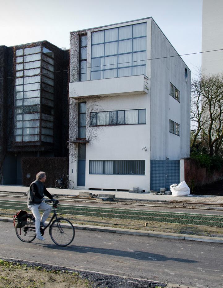 The Guiette House in Antwerp, a narrow white façade, with a cyclist passing by