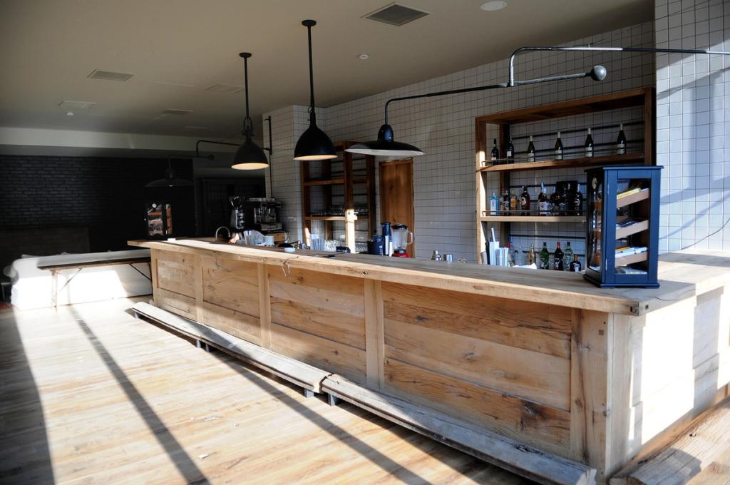 A solid wood bar counter with pendant lights and white tiling