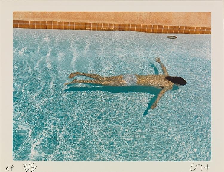 A photograph of a person swimming in the clear blue water of a pool