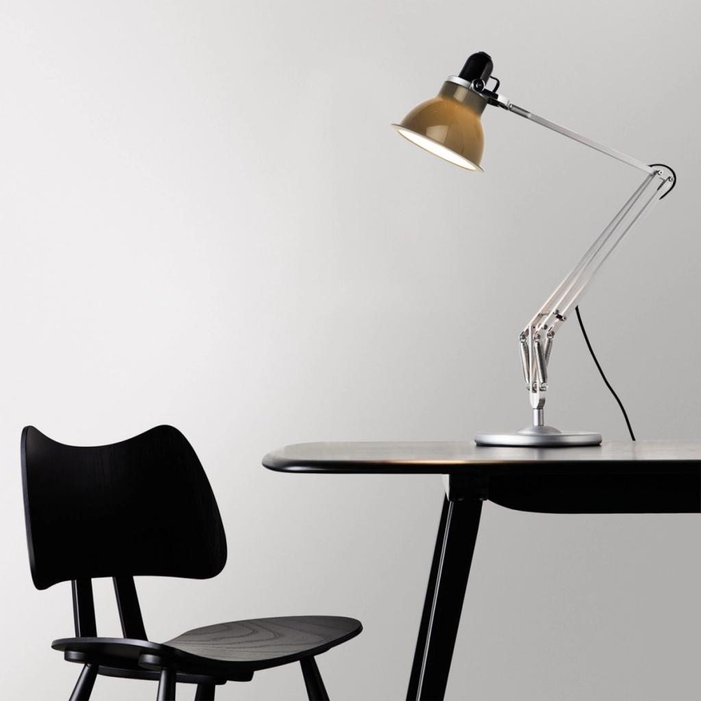Лампа Anglepoise с охристым плафоном на столе рядом с чёрным деревянным стулом