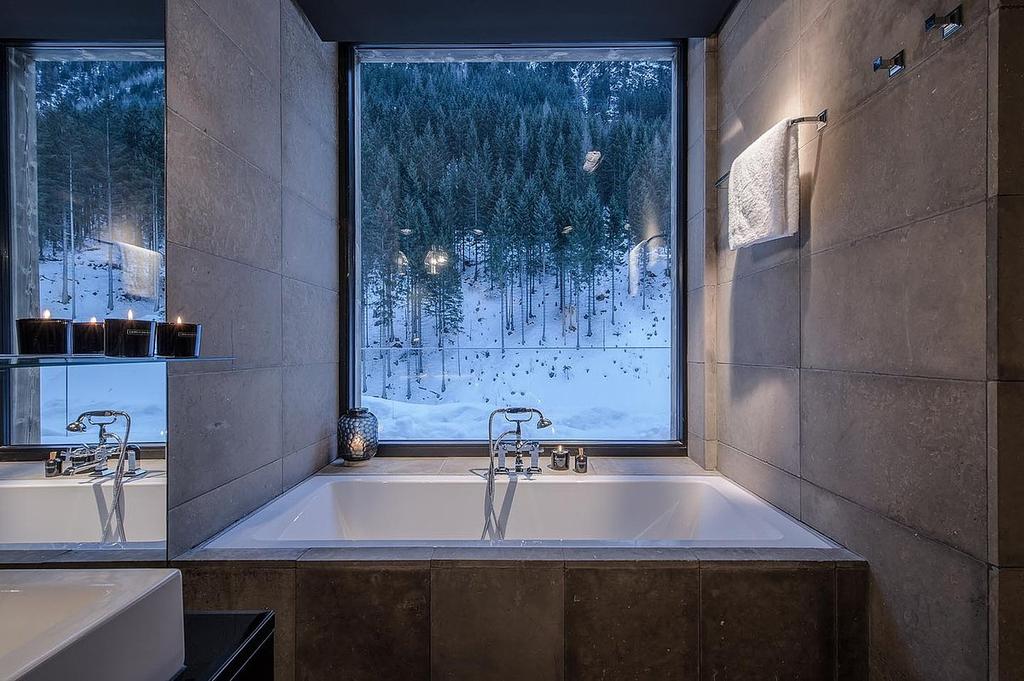A bathroom with a window onto the snow-covered conifer forest at Hotel Zhero