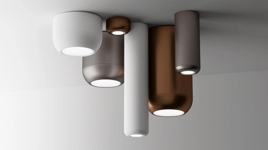 A cluster of cylindrical ceiling lights in white, bronze and graphite, designed by Dima Loginov