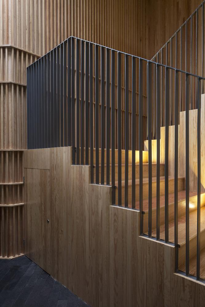 The wooden staircase of Walden Dos School with slender black metal railings