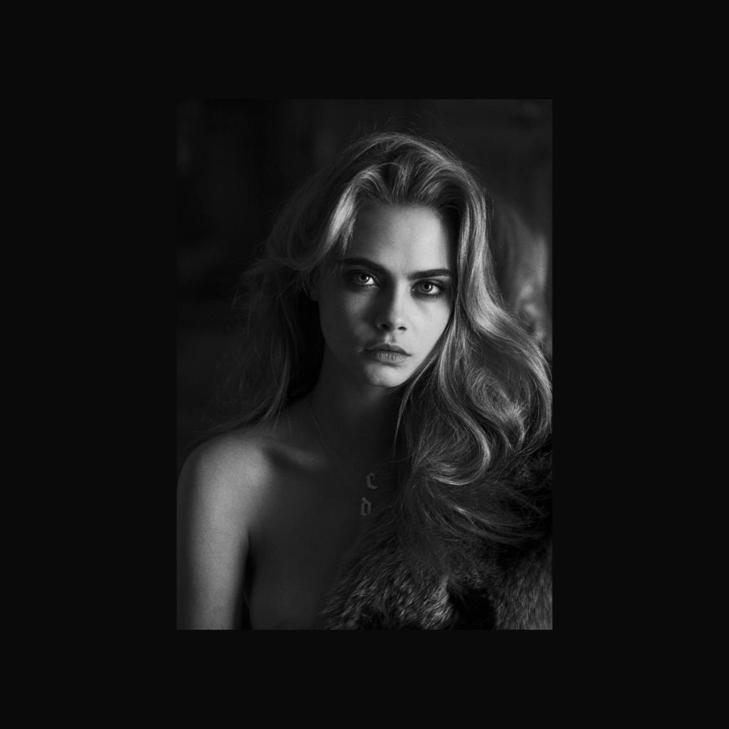 A black-and-white portrait of a fair-haired woman with loose hair against a dark background