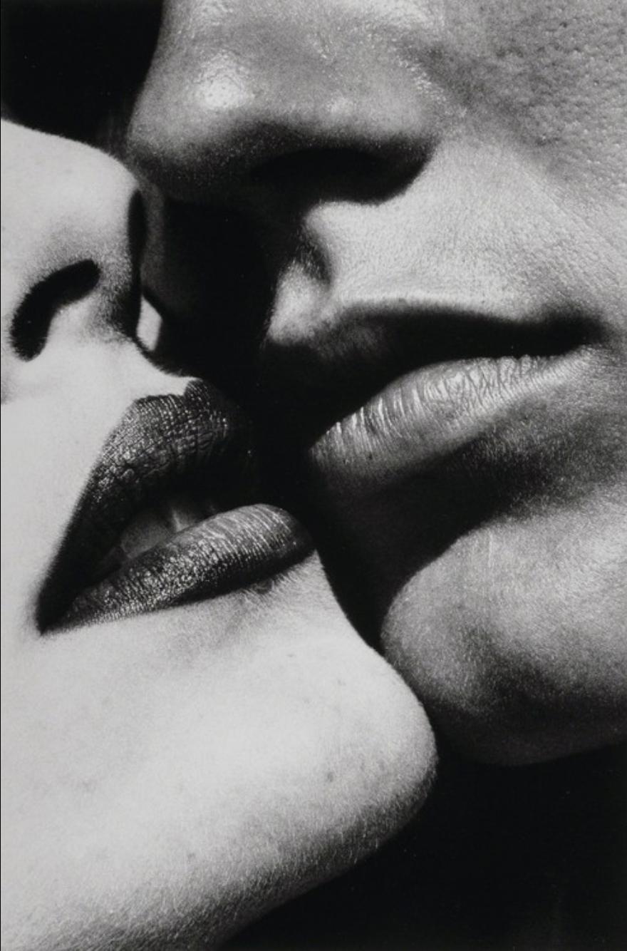 Close-up of a man's and a woman's faces, the woman wearing dark lipstick, caught just before a kiss
