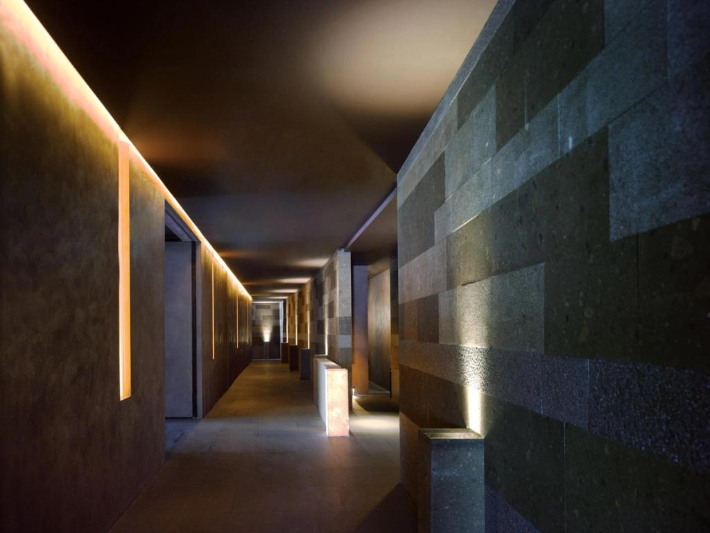A dimly lit corridor with rough stone masonry and narrow slits of light