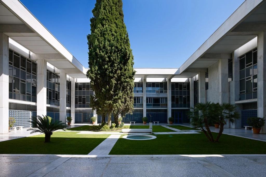 A low-angle view of the marble piers and canopy of the US Embassy building in Athens