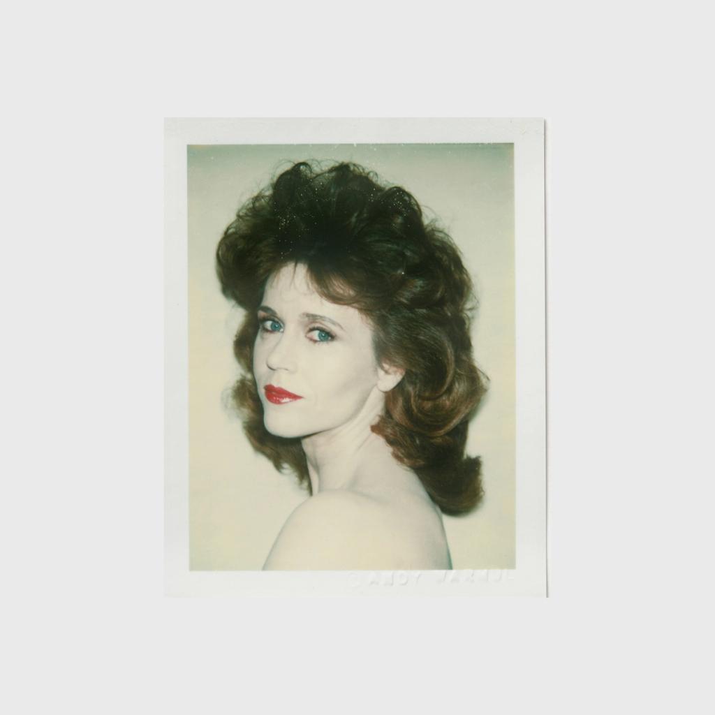 A Polaroid portrait of a woman with voluminous hair, turned over her shoulder, her shoulders bare