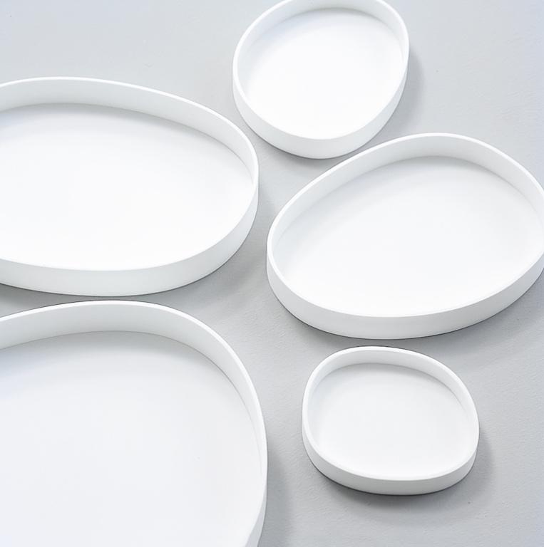 A set of white Vertigo trays in varying sizes with rounded, organic edges