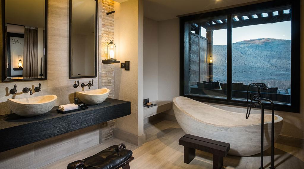 A bathroom with stone basins and a panoramic window looking out to the mountains of Oman