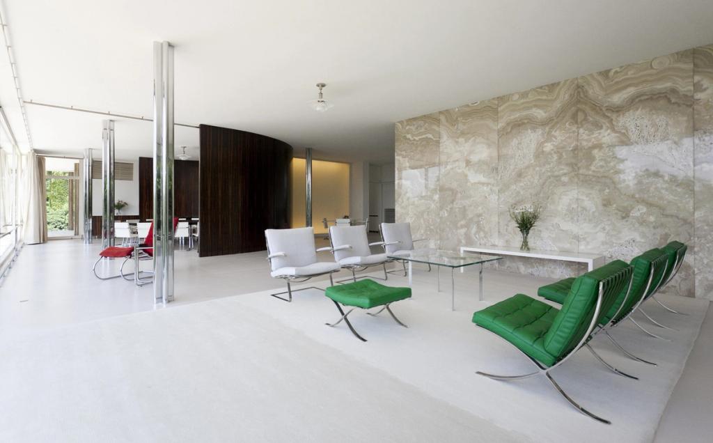 The living room of Villa Tugendhat with an onyx wall, Barcelona chairs and chrome columns