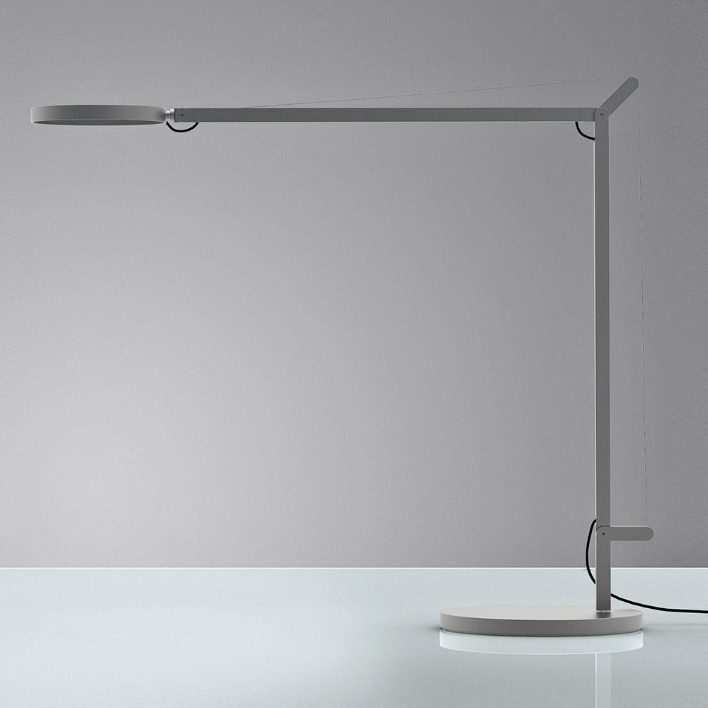 A grey LED desk lamp with a long, slender arm and a flat circular head