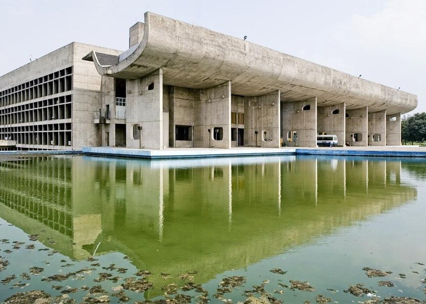 The concrete Palace of the Assembly in Chandigarh with its portico canopy, reflected in a pool of water
