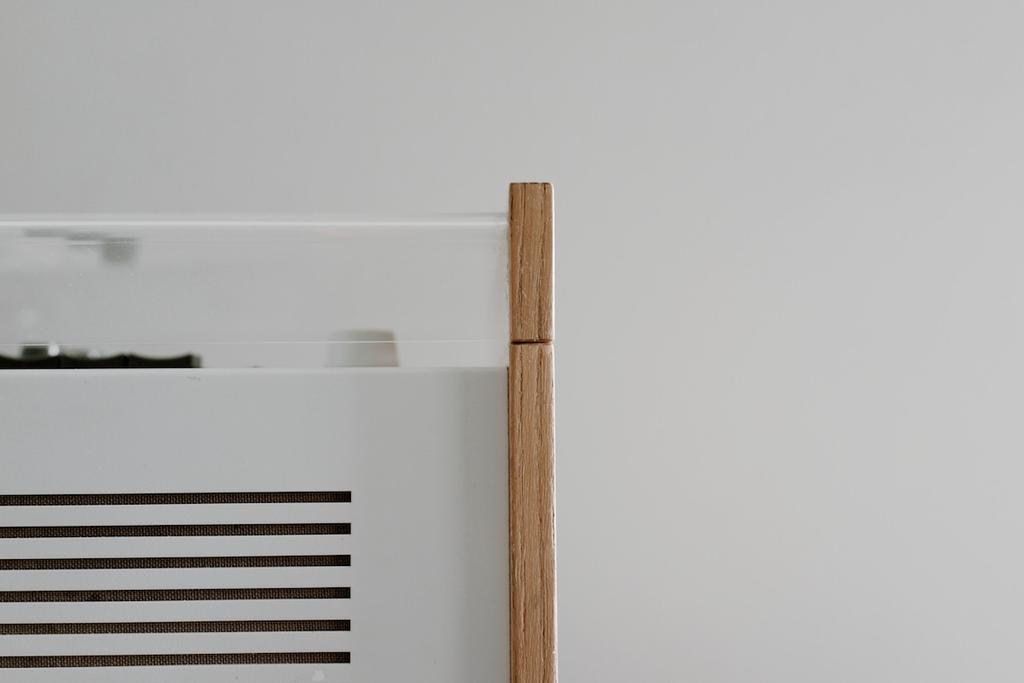 A hand holds a light-coloured rectangular latch against the wooden frame of the lid