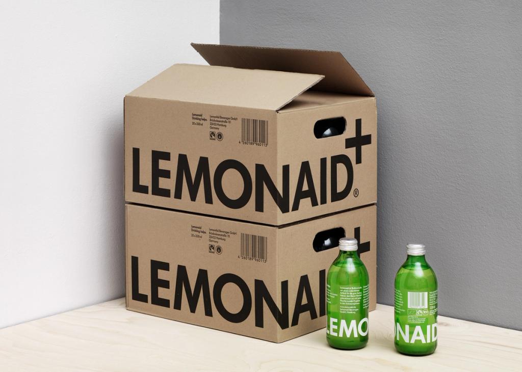 Две коробки Lemonaid с крупным чёрным логотипом и зелёные бутылки рядом