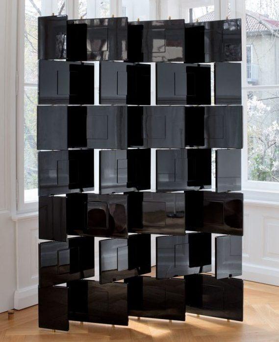 Eileen Gray's black lacquer folding screen of articulated rectangular panels beside a window