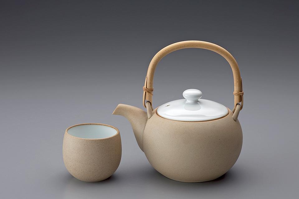 Beige spherical teapot with a bamboo handle and a cup