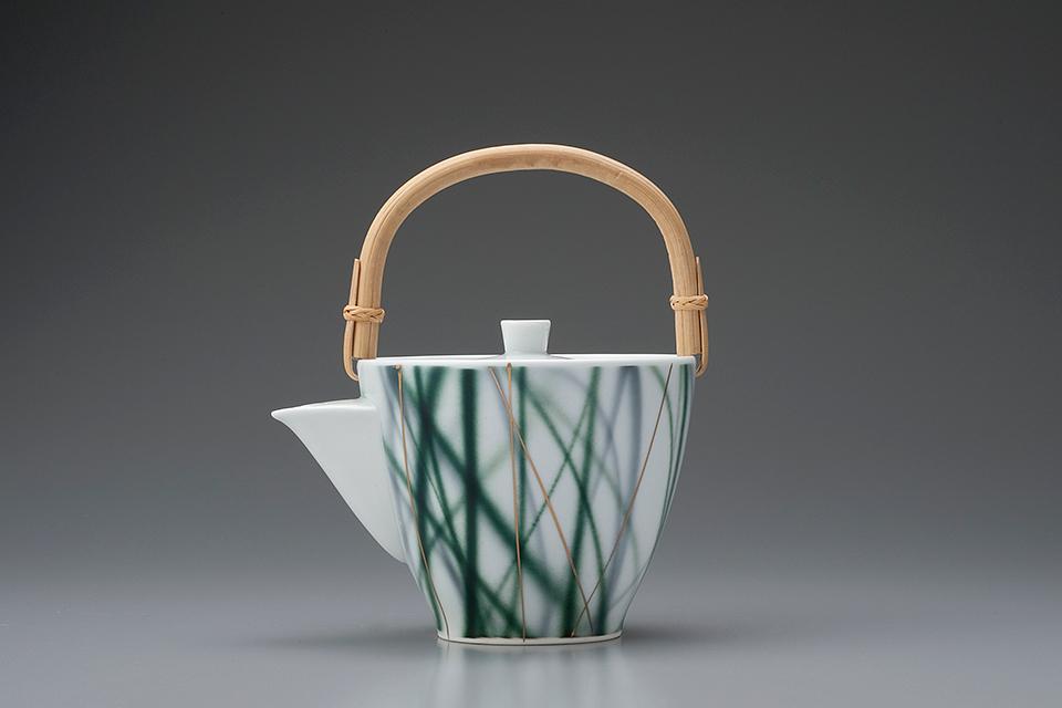 Porcelain teapot with a bamboo handle and a botanical motif of green herbs