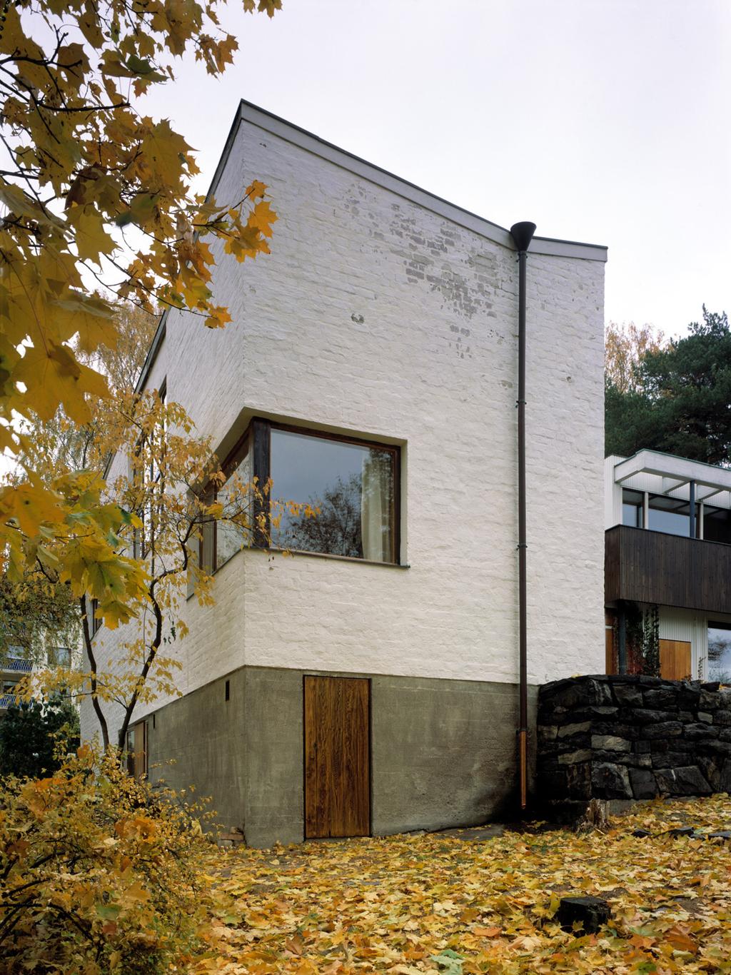 Alvar Aalto's house in Helsinki, a corner of the white brick facade with a ribbon window in autumn