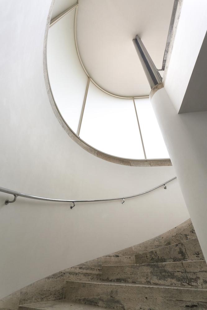 The spiral staircase of Villa Tugendhat with travertine treads and a chrome handrail