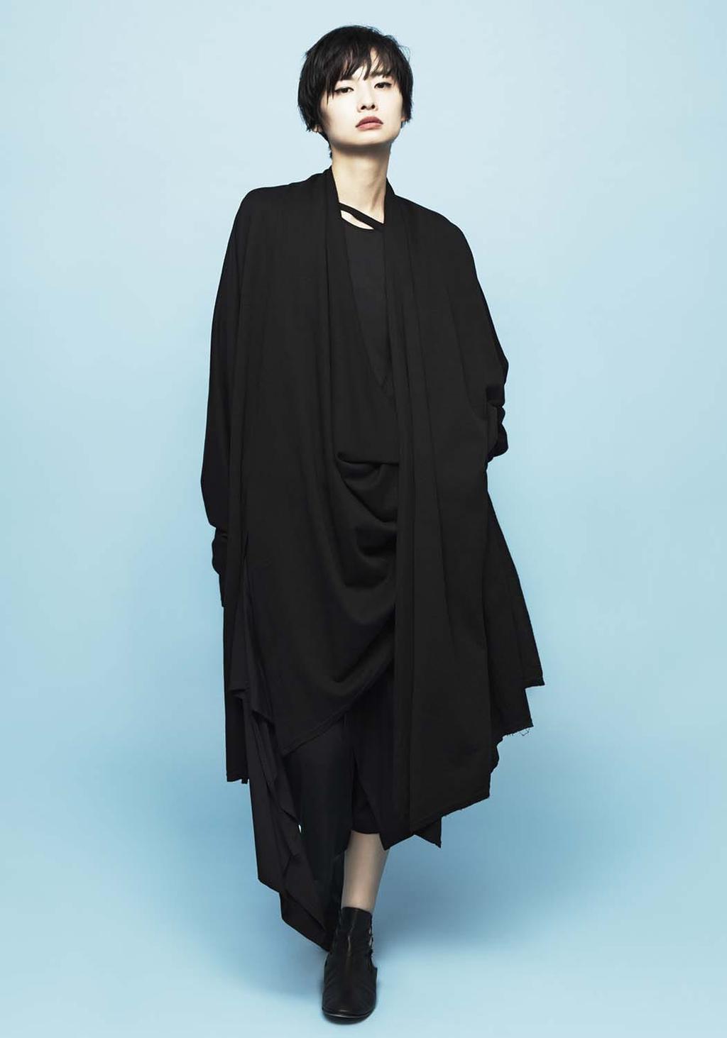 A model in a long black draped cardigan worn over an all-black ensemble